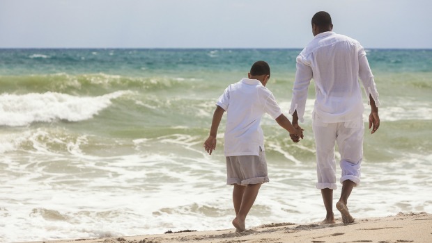 Padre e hijo caminando por la playa.